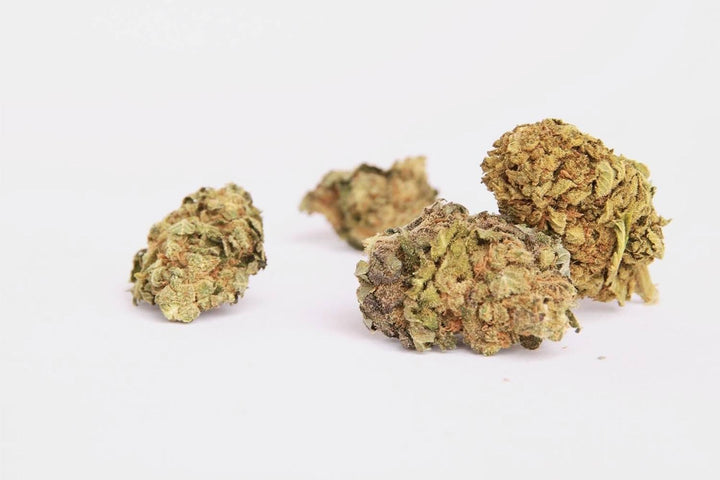 This image displays a collection of Melonade CBD flowers strain, characterized by their green hue with purple flecks.